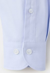 Poignet de chemise bleu clair avec deux boutons blancs et couture détaillée sur tissu texturé.