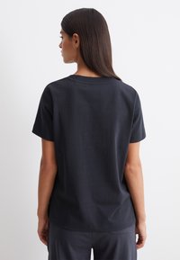 Mörkgrå kortärmad t-shirt med rund halsringning, slät textur och avslappnad passform, visad bakifrån.