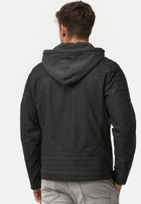 Mustat nahkatakki harmaalla hupulla, jossa on uritetut olkapäät ja takakappale, vetoketjusuljenta ja sileä viimeistely.