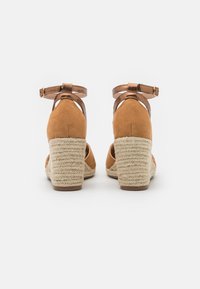 Sandali con tacco in suede color sabbia, dotati di una piattaforma e un tacco in corda intrecciata, con un cinturino in metallo e design aperto sul retro.
