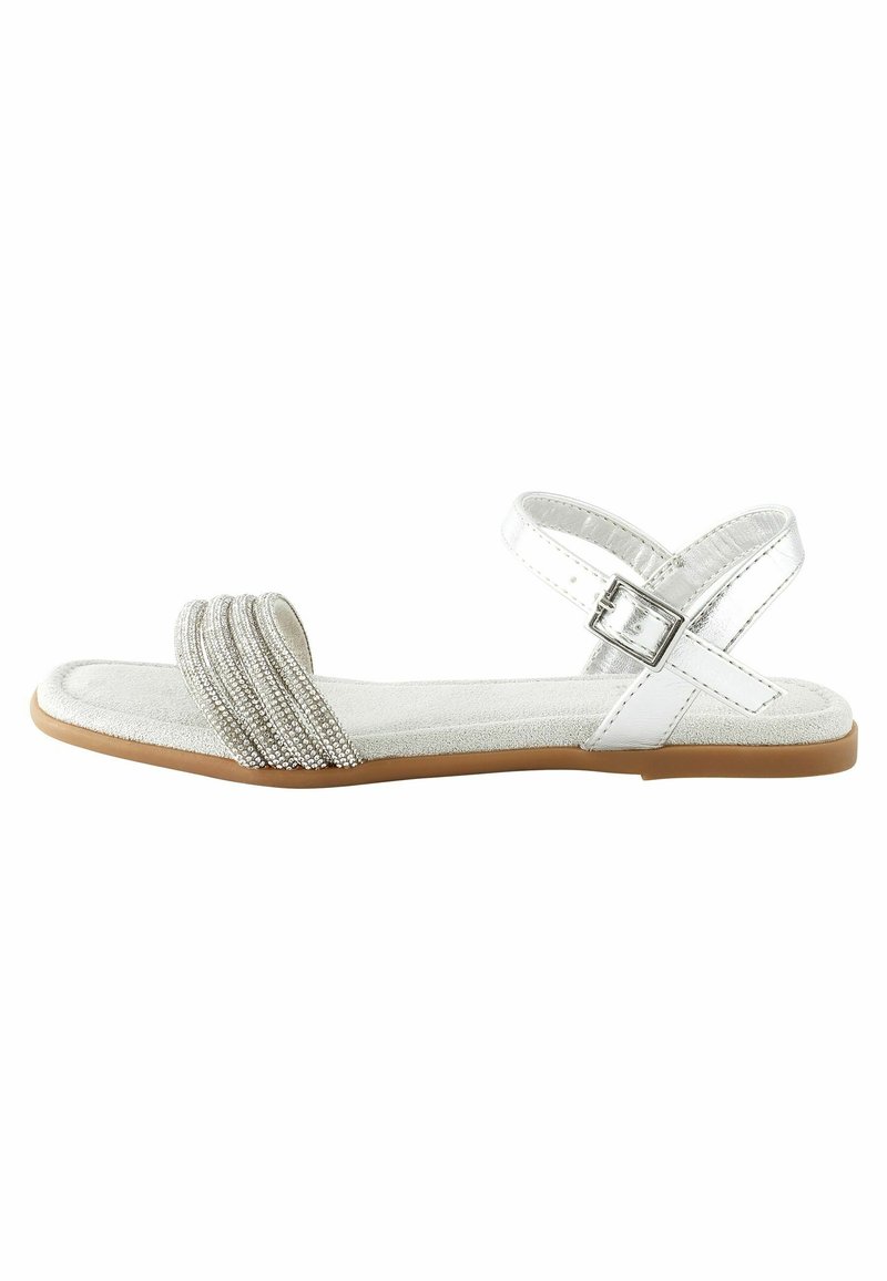 Platte sandalen met een witte synthetische bovenkant, voorzien van een crisscross bandontwerp versierd met zilveren embellissementen en een rubberen zool.