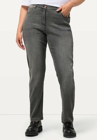 Pantalones de mezclilla gris con un diseño de pierna recta, que cuentan con cinco bolsillos, botón de metal y un ligero desvanecimiento. Llevados con zapatos de plataforma negros.