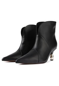 Des bottines en cuir noir présentent un bout pointu, un design découpé unique et un accent de talon argent métallique, ajoutant une touche moderne.