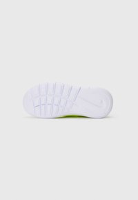 Semelle blanche texturée d'une chaussure de sport avec le logo Nike, photographiée par le dessous sur un fond blanc uniforme.