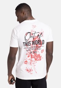 Weißes Baumwoll-T-Shirt mit rotem Blumenmuster und schwarzem Text auf der Rückseite. Verfügt über einen Rundhalsausschnitt und kurze Ärmel, lockere Passform.