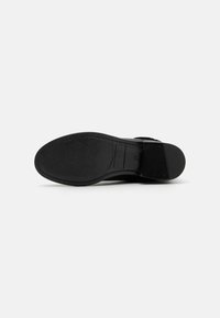 Sole di scarpa in pelle nera con una texture liscia, ritaglio rettangolare e cuciture delicate lungo i bordi. Design della punta piatta e arrotondata.