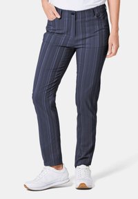 Marineblauwe broek met strepen in een lichtgewicht, gladde stof. Voorzien van een ritssluiting, voorzakken en een getailleerde pasvorm. Draagt wit sneaker.