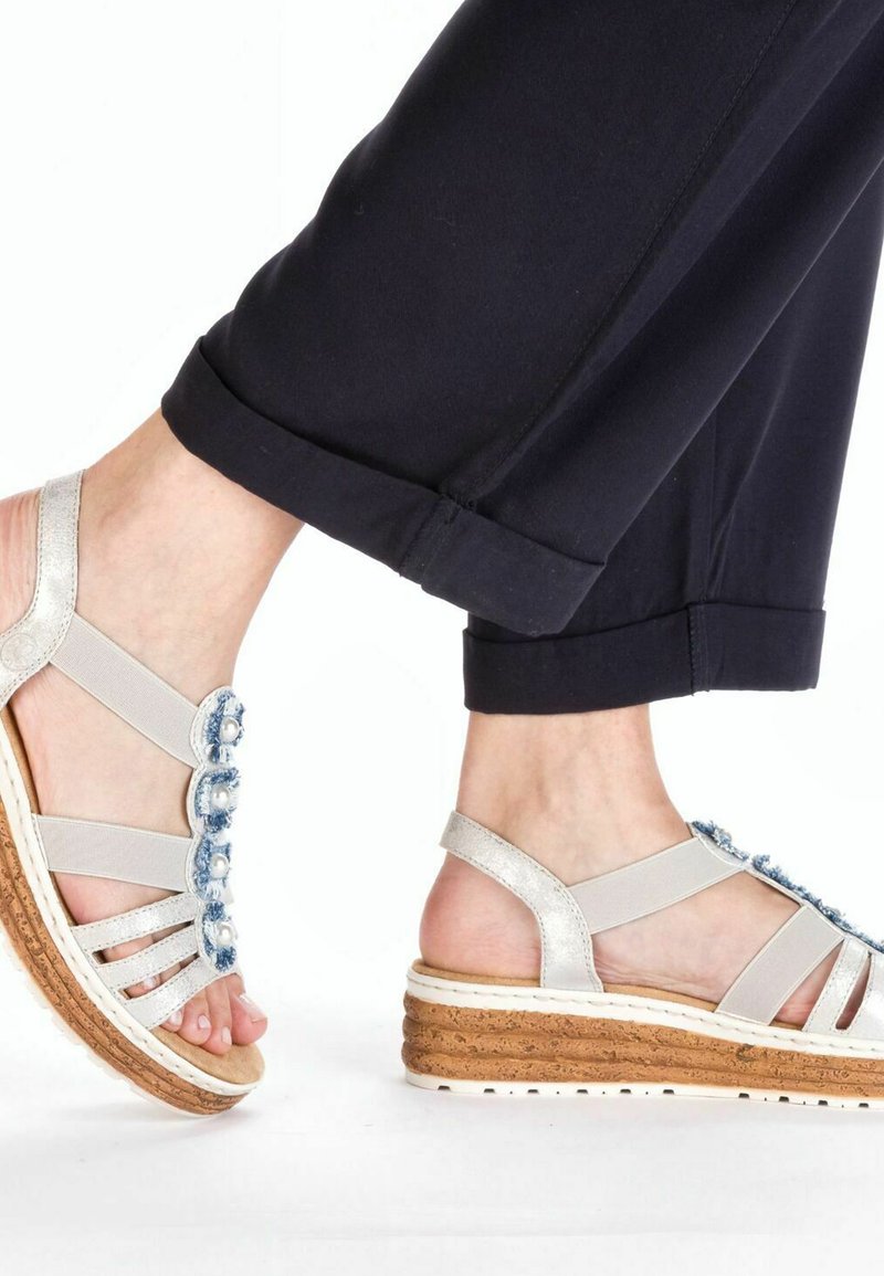Sandales compensées avec une semelle en liège, des brides métalliques argentées et des embellissements en denim en forme de fleur. Arrière fermé avec un design ouvert à l'avant.