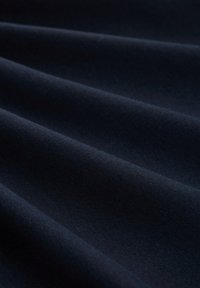 Ciemnoniebieska tkanina o gładkiej fakturze, z subtelnymi fałdami i jednolitym wzorem tkania. Idealna do odzieży lub tapicerki.