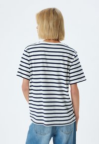 Stribet T-shirt i hvid med marineblå striber, med korte ærmer, rund halsudskæring og en afslappet pasform. Blødt bomulds materiale.