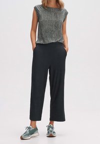 Haut gris léger et texturé à manches courtes, assorti d'un pantalon large et sombre. Complété par des baskets vert menthe.