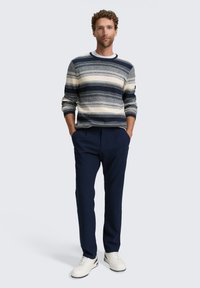 Jersey a rayas en navy y blanco con cuello redondo, combinado con pantalones navy y zapatillas blancas. El tejido parece suave con un acabado texturizado.