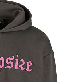 Hoodie gris foncé avec une poche avant. Présente un design de texte brodé rose. Tissu doux avec une coupe décontractée, y compris une capuche avec cordon.