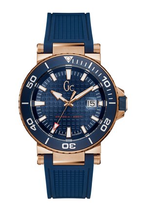 Blue silicone strap watch with a textured dark blue dial, gold-tone accents, large white hour markers, and a red second hand. Water-resistant to 100m.