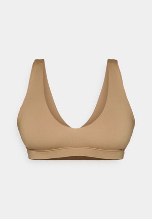 Beige, seamless bra with a low scoop neckline and wide straps. Made from smooth, stretchy fabric, offering a fitted shape.