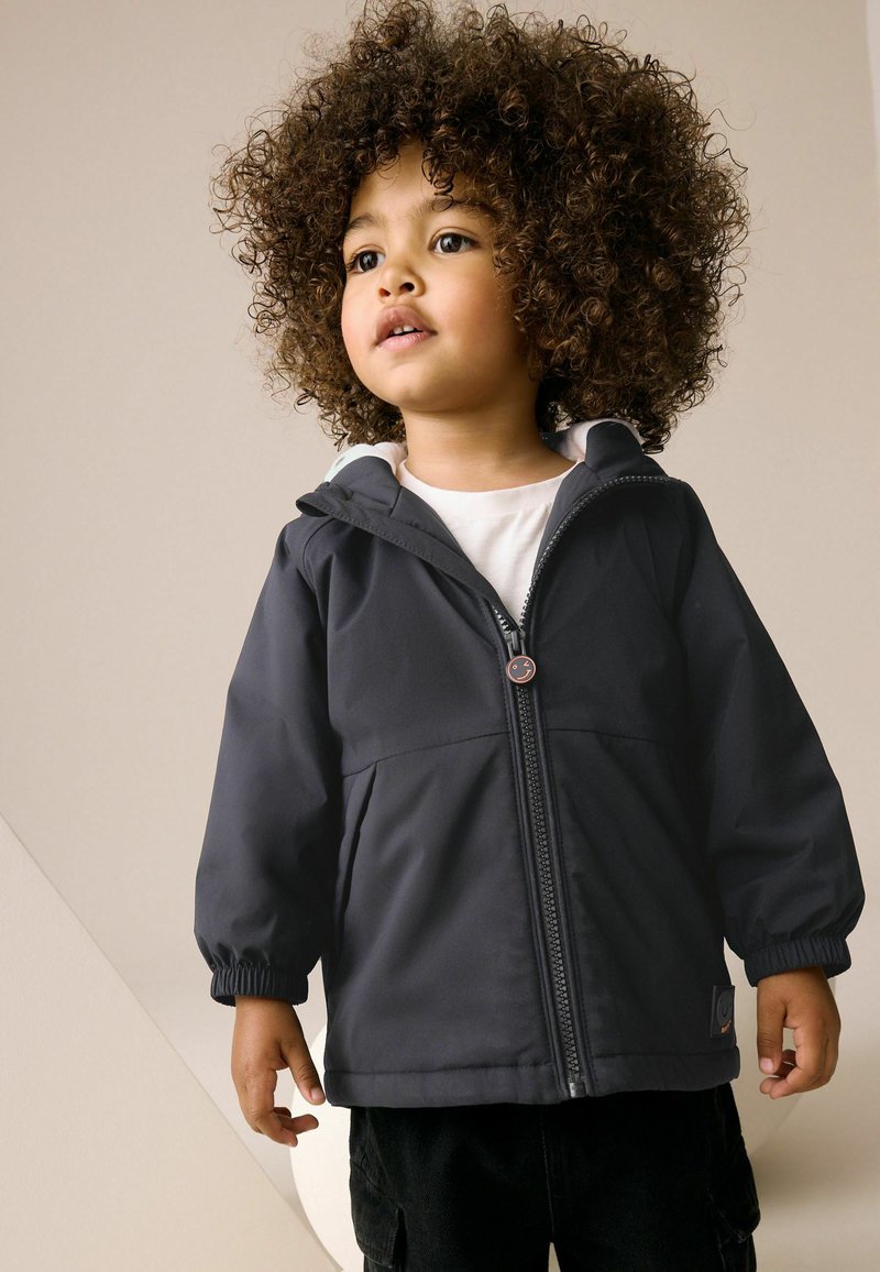 Schwarze Kapuzenjacke mit einem Frontreißverschluss, elastischen Bündchen und Seitentaschen. Sie verfügt über ein helles Innenfutter und ein rundes Logo am Reißverschluss-Zug.