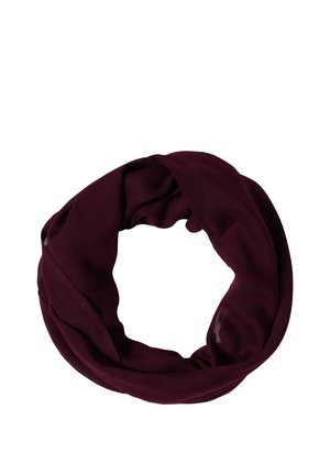 Lachende vrouw die een wit kortemouwen topje, blauwe spijkerbroek en een bordeaux infinity sjaal draagt tegen een effen achtergrond.
