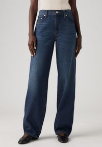 Wijde spijkerbroek in donkerblauwe denim, uitgerust met een hoge taille, vijf zakken en contrasterende stiksels. Glad materiaal met een relaxte pasvorm.
