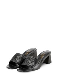 Zwarte leren hoge muiltjes met een brede band die een gewatteerd patroon heeft. Vierkante neus en een dikke blokhak. Logo gedrukt op de binnenzool.