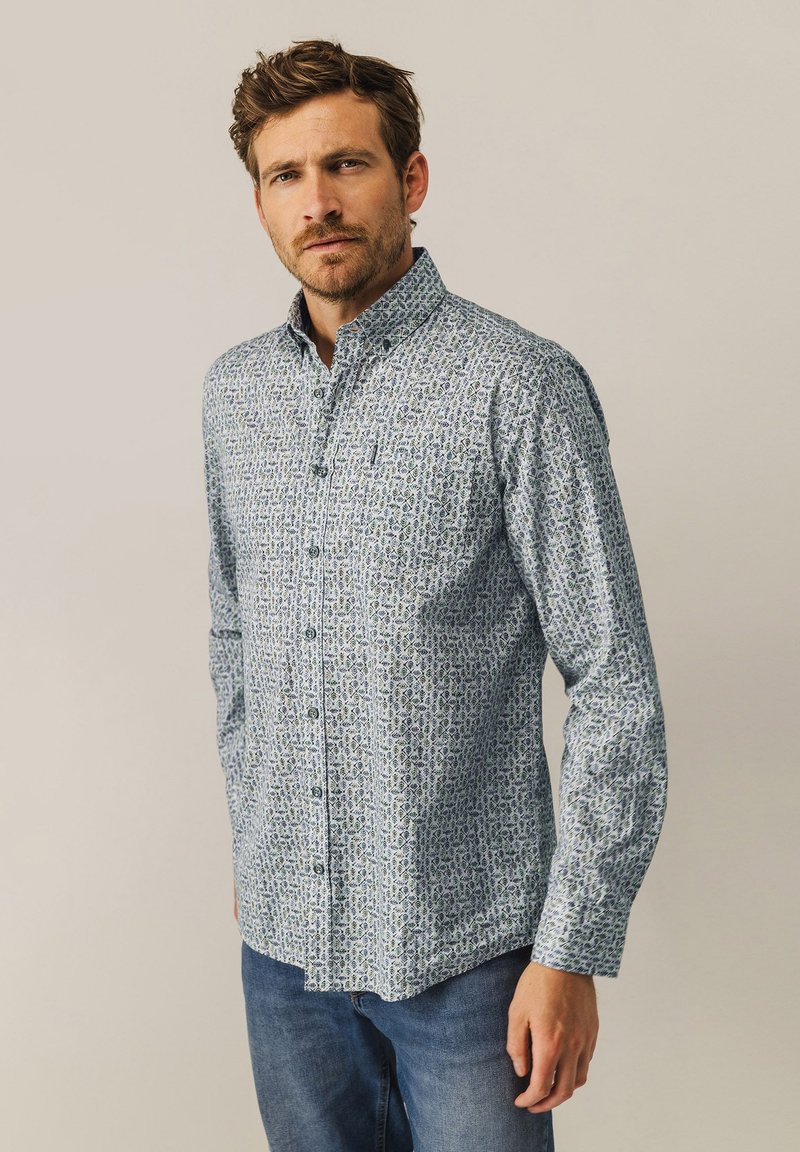 Button-up-Hemd in hellblau mit grünem Blumenmuster, langärmlig, mit klassischem Kragen, kombiniert mit blauen Jeans.