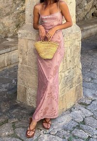 Roze bloemenpatroon, mouwloze maxi jurk met dunne bandjes, gecombineerd met bruine sandalen met riempjes en een geweven strohandtas.