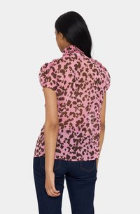 Prosojna roza bluzica z rjavim živalskim vzorcem, kratkimi napihnjenimi rokavi in nabrano ovratnikom. Material ima lahek, tekoč teksturo.