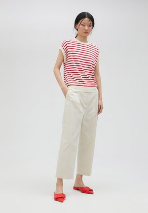Top de manga corta a rayas en rojo y blanco, combinado con pantalones de pierna ancha color crema. Acabado con zapatos planos rojos. Diseño simple.