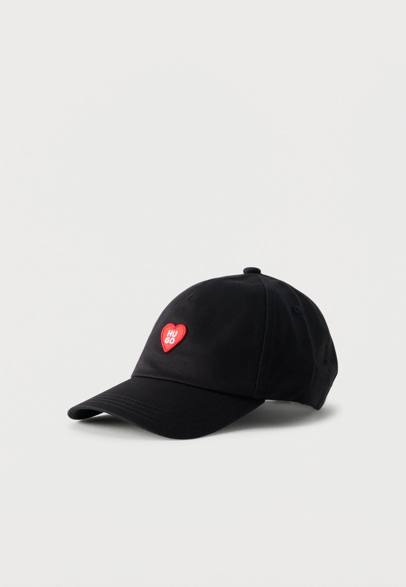 Μαύρο καπέλο μπέιζμπολ με κόκκινο μπαλώμα σε σχήμα καρδιάς κεντημένο με τη λέξη "HUGO" στο κέντρο μπροστά, πάνω σε απλό λευκό φόντο.