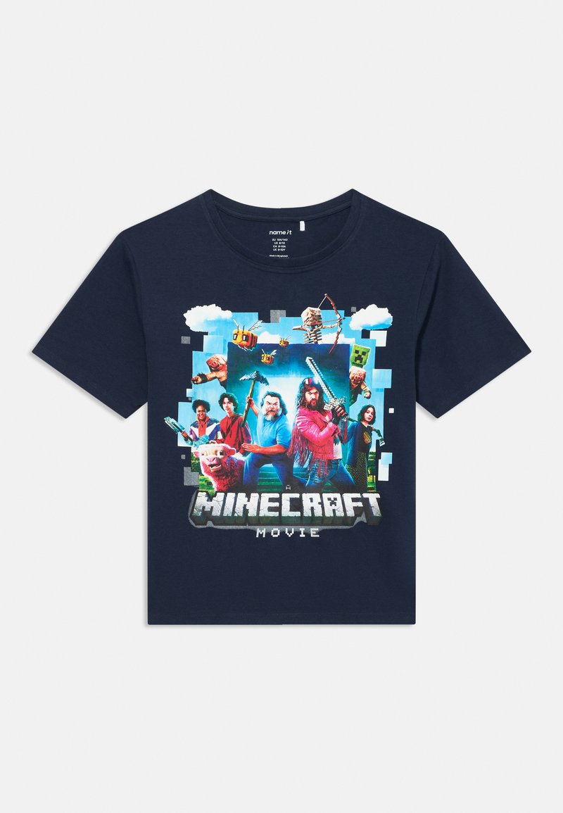 Tamsiai mėlynas medvilninis marškinėliai su spalvinga grafika, vaizduojančia veikėjus ir elementus iš Minecraft, apačioje esantis tekstas "Minecraft filmas".