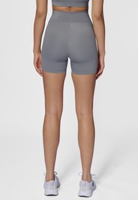 Shorts gris taille haute en matériau extensible, se terminant à mi-cuisse, avec une texture lisse et des détails cousus à la taille.