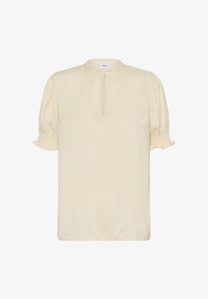 Blouse couleur crème avec manches courtes bouffantes, poignets froncés et encolure avec ouverture en forme de clé. Tissu doux avec une texture lisse.