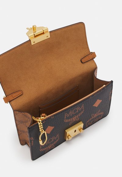 Black leather handbag with brown accents and embossed patterns. Gold hardware closure, interior suede lining, and card slots visible.