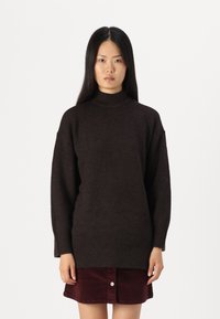 Tumepruun, ülikerge turtleneck-sviiter ribatud äärte ja mansettidega. Kandmine burgundi värvi kammkarva seelikuga, millel on esipaneelil nupud.