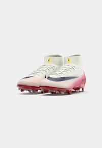 Voetbalschoenen met een wit en roze verloopontwerp, voorzien van een gestructureerde bovenkant, slanke vorm en transparante rode zool met noppen.