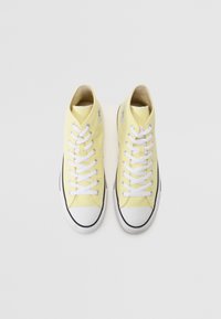 Gelbe High-Top-Sneaker aus Canvas mit weißen Schnürsenkeln, Gummispitzkappen und schwarzer Details um die Sohle, mit Markenlogo auf der Außenseite.