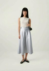 Light gray ribbed top and metallic silver midi skirt with seams. Model carries a black handbag and wears black shoes with straps.