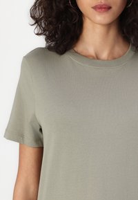 Olive green short-sleeve t-shirt with a round neckline, made of soft cotton fabric. Smooth texture and minimal stitching detail.