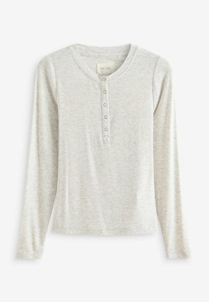 Langærmet henley skjorte i lys grå ribbet stof med rund halsudskæring og fire knapslukker. Har en blød tekstur og tætsiddende design.