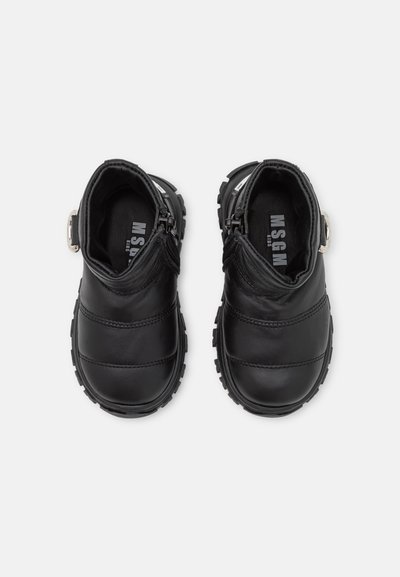 Botas de tornozelo em couro preto apresentam um bico arredondado, painéis texturizados e um fecho de correr de lado. A sola de borracha com padrão proporciona aderência e durabilidade.