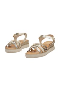 Sandalias metálicas doradas con correas entrecruzadas, plantilla acolchada y una suela de plataforma beige clara. Tira ajustable en el tobillo con cierre de hebilla.