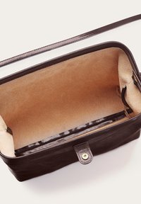Brun läderväska med en slät yta, rektangulär form och ett lätt fodrat beige inre. Utrustad med knappstängning och axelrem.