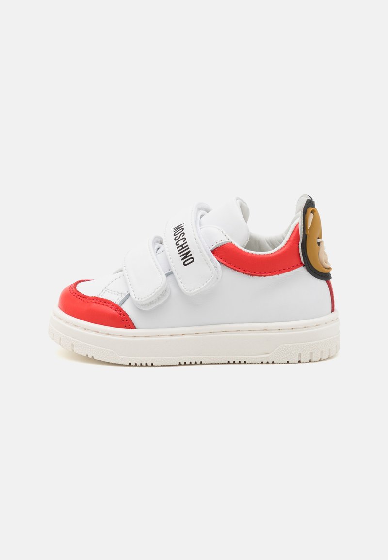 White sneaker with red accents, synthetic upper, Velcro straps, textured rubber sole, and a cartoon bear detail at the heel.