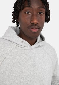 Szara bluza z kapturem wykonana z miękkiego, teksturowanego materiału, z przednią kieszenią i regulowanym kapturem na sznurku, z zatrzaskami przy dekolcie.