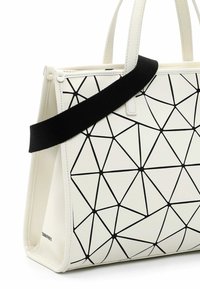 Biała torba na ramię w geometryczny wzór z czarnymi liniami, z solidnymi uchwytami i odpinanym paskiem, oferująca różne opcje noszenia.