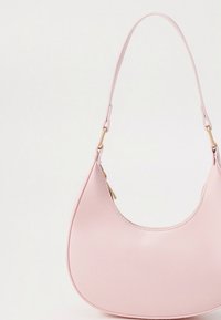 Sac à main en similicuir rose avec une forme incurvée en croissant. Il présente une seule bandoulière et un accent en métal doré. Texture lisse et design minimaliste.