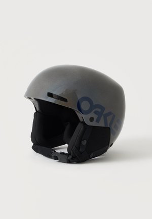 Casco sportivo Oakley grigio con coperture auricolari imbottite nere e cinturino regolabile per il mento su sfondo bianco.