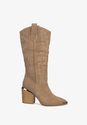 Bota de estilo occidental en ante color marrón claro con bordados intrincados, punta afilada y tacón de madera apilada. Incluye una lengüeta para facilitar el uso.