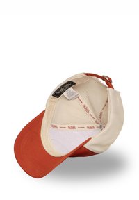 Casquette de camionneur avec un dos en mesh beige et une visière en coton couleur rouille. Elle comporte une étiquette et une bande intérieure avec un marquage répétitif.