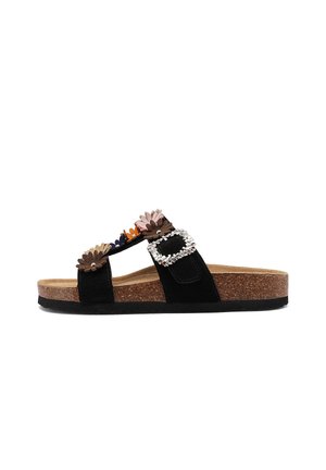 Sandalia tipo slide negra con suela de corcho, decorada con aplicaciones florales de colores y una gran hebilla de piedras brillantes en la correa.