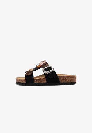 Sandalia tipo slide negra con suela de corcho, decorada con aplicaciones florales de colores y una gran hebilla de piedras brillantes en la correa.